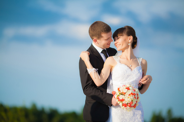 Pareja de boda joven - novio y novia recién casados posando al aire libre
 - Foto, imagen