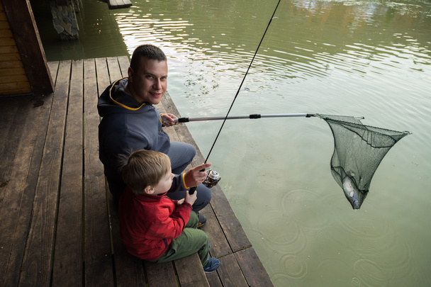 Père et fils dans le processus de capture de poissons
 - Photo, image