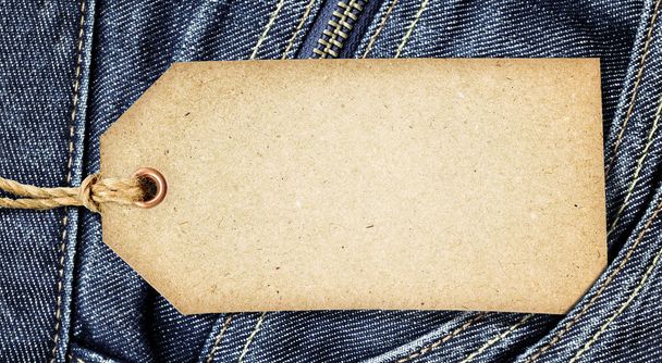 Винтажная бумажная бирка на синей джинсе
 - Фото, изображение