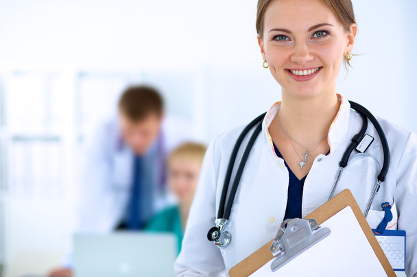 Attractive female doctor  with folder in front of medical group - Foto, imagen