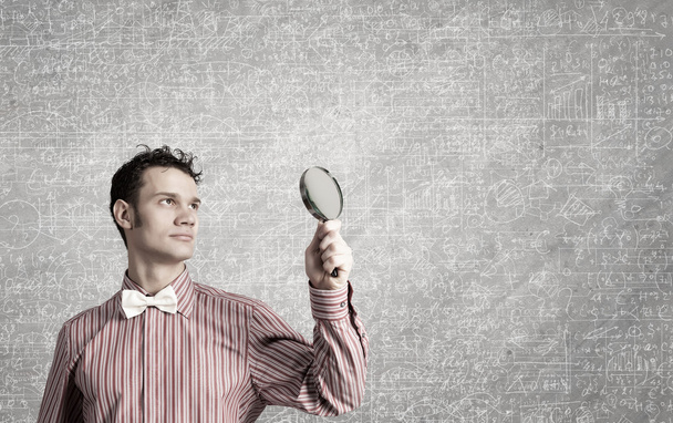 Guy looking in magnifying glass - Foto, afbeelding