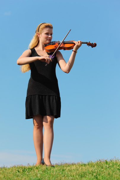 Girl plays violin against sky - Фото, изображение