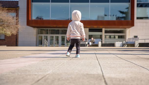 Little girl with sneakers and hoodie standing outdoors - Photo, image