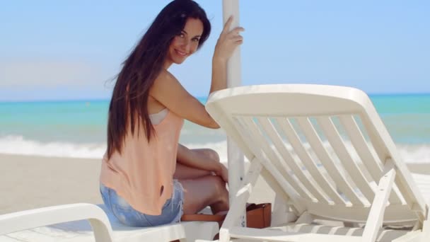 Uśmiechający się ładny na leżaku na plaży - Materiał filmowy, wideo
