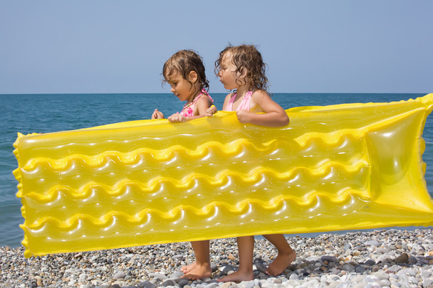 Two pretty little girls bearing in hands inflatable mattress on - Photo, image