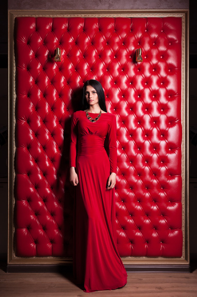 young woman in red dress standing near wall - Fotó, kép