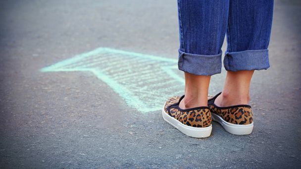 vrouwelijke voeten en tekening pijl op de stoep achtergrond - Foto, afbeelding