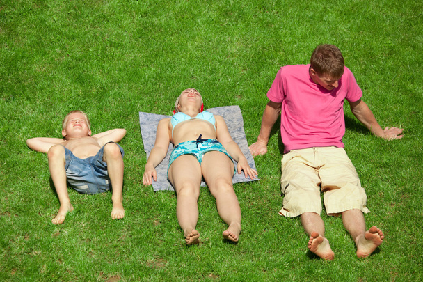Семья с мальчиком, отдыхающим на траве, вид сверху
 - Фото, изображение