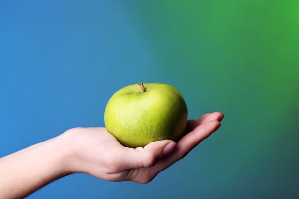 Female hand with apple on colorful background - Photo, Image