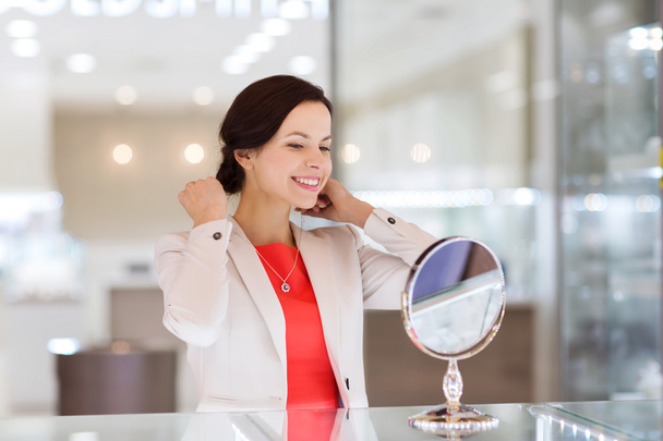 happy woman choosing pendant at jewelry store - Foto, Imagen