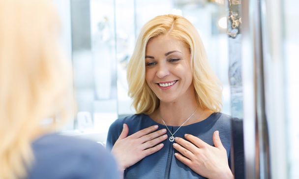 happy woman choosing pendant at jewelry store - Foto, Imagen
