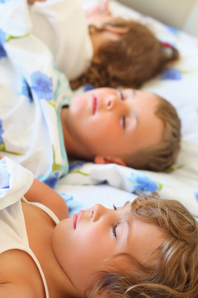 Children three together sleeping on bed in cosy room, lying on b - 写真・画像