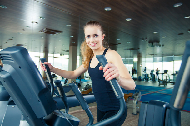Portrait of pretty girl training on special sport equipment in gym - Foto, Bild