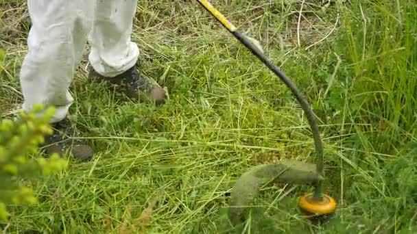 kaszálás a zöld fű-lejtőn üzemanyag Trimmer ember közelről - Felvétel, videó