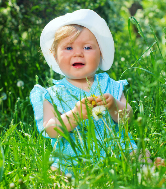 Little girl sitting in the grass in the park - 写真・画像