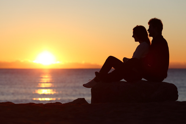 Couple silhouette sitting watching sun at sunset - Zdjęcie, obraz