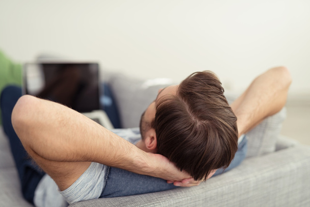 Man lying resting on a sofa at home - Foto, Bild