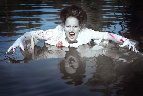Mujer vampiro vestida con camisa blanca sangrienta en el río
 - Foto, imagen
