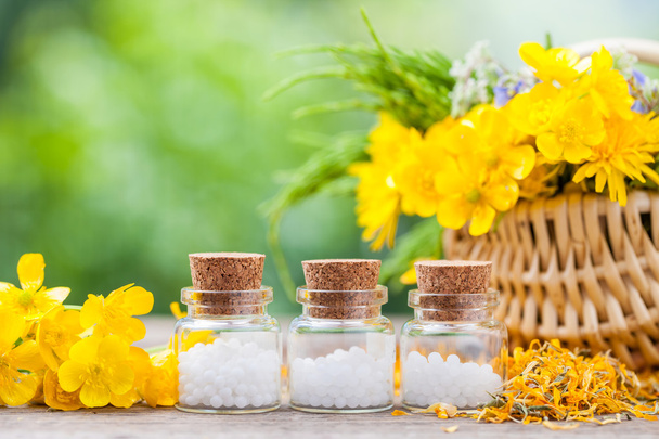 Bottles of homeopathy globules and healthy herbs in wicker baske - Photo, image