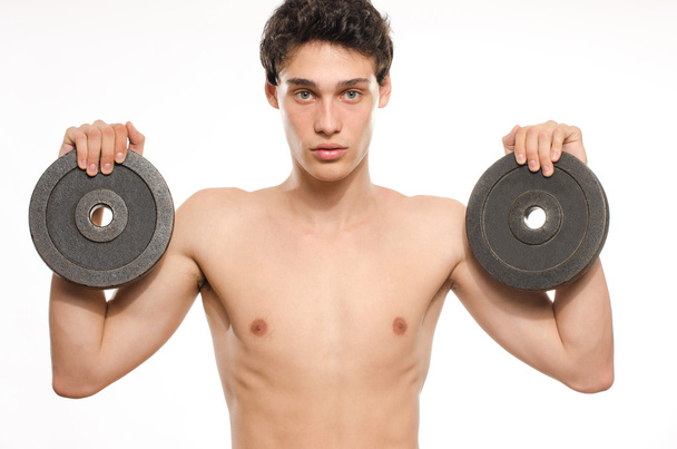 Skinny man training his bicep muscle. Beautiful teenager lifting two dumbbells.Anorexic young man training to become stronger - Foto, imagen