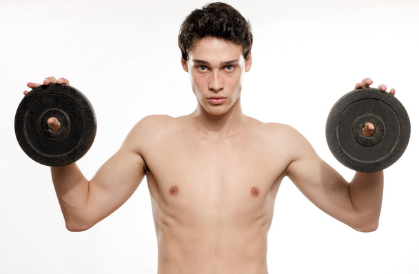 Skinny man training his bicep muscle. Beautiful teenager lifting two dumbbells.Anorexic young man training to become stronger - Foto, Bild