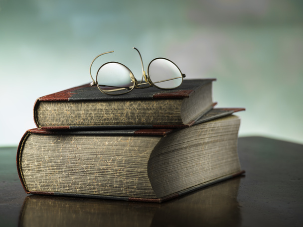 Старые книги с антикварными очками для чтения на красочном фоне
 - Фото, изображение