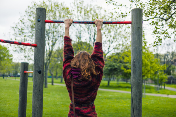 Woman doing pull ups in a park - Foto, Imagem