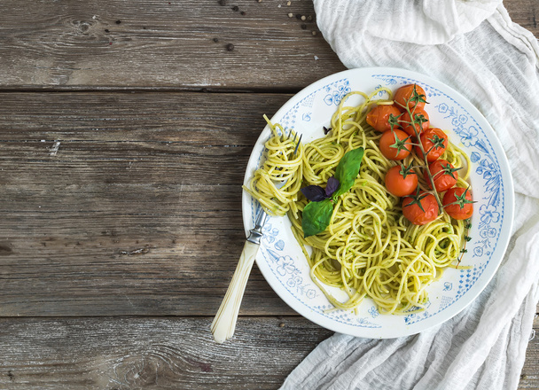 Pasta spaghetti with pesto sauce, basil, baked cherry-tomatoes on rustic wooden tabke dark table, top view - Fotografie, Obrázek