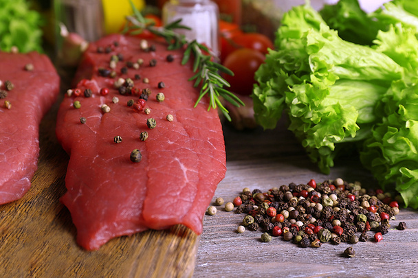 Raw beef steak with spices and greens on table close up - Φωτογραφία, εικόνα