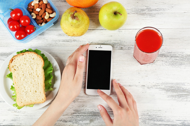 Food and mobile phone in female hands - Valokuva, kuva