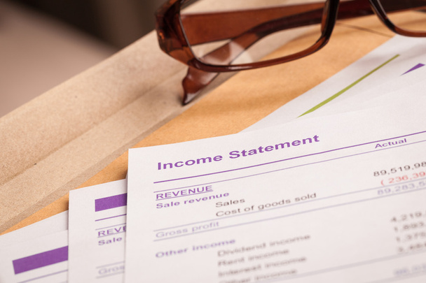 Income statement letter on brown envelope and eyeglass, business - Photo, Image