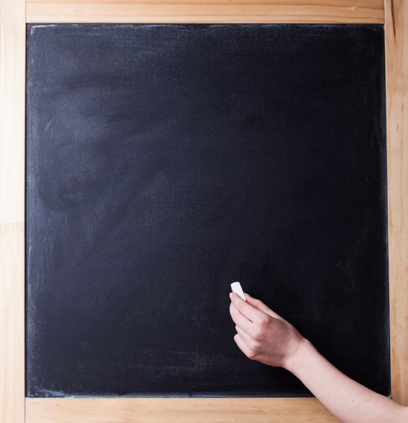 de menselijke hand begint schrijven met krijt op een schone schoolbord - Foto, afbeelding