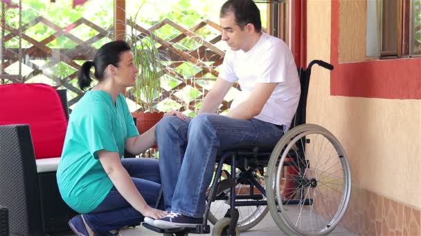 Nainen sairaanhoitaja lohduttaa surullinen mies istuu pyörätuolissa
 - Materiaali, video