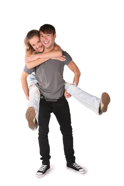 Girl embraces boy from behind, he holds her on the hands for the legs on th - Photo, image
