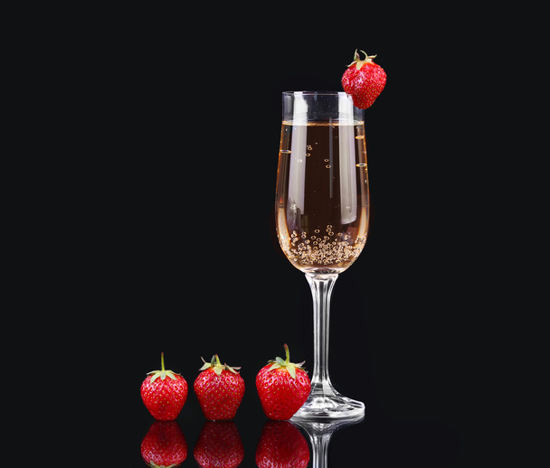 Glass of cold champagne with strawberries on a black background - Valokuva, kuva