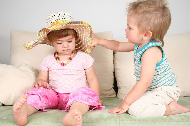 Boy and girl on sofa in straw hat with beads - Фото, зображення