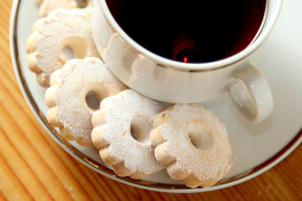 Biscotti italiani Canestrelli sul piattino di una tazza di tè nero
 - Foto, immagini