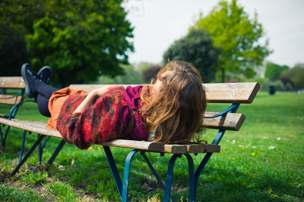 Woman lying on a bench in the park - Фото, изображение