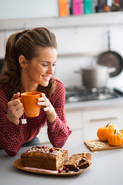 Woman smiling in kitchen holding mug with fresh fruit loaf - Foto, immagini
