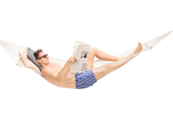 Man in a hammock reading a newspaper - Photo, image