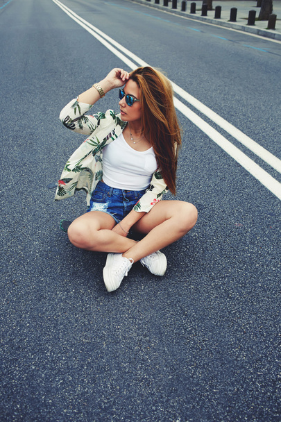 hipster girl sitting  in the middle of asphalt road - Zdjęcie, obraz