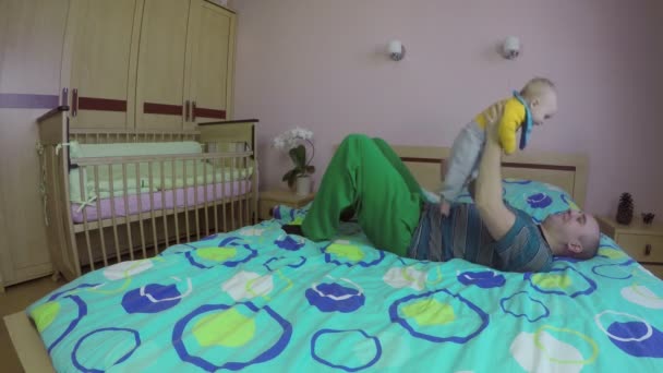Baba ve bebek yatakta birlikte oynar. Mutlu ebeveyn kavramı. 4k - Video, Çekim