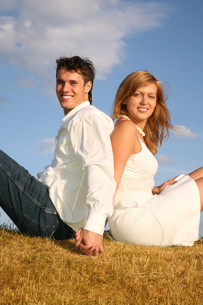 Couple sit on meadow back to back - Photo, image