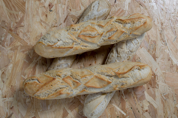 čtyři bagety na dřevěným pozadí - chutný chléb - Fotografie, Obrázek