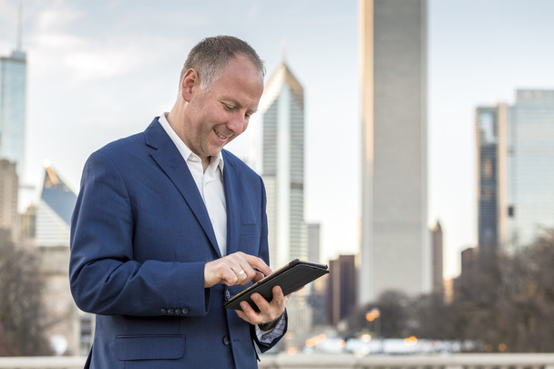 Businessman with tablet in front of office buildings - Photo, Image