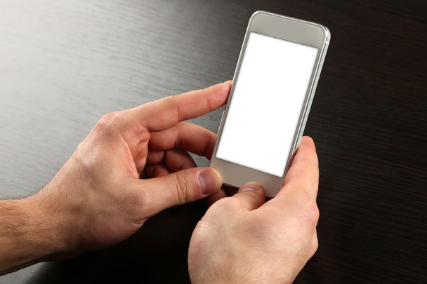 Hands holding smart mobile phone on wooden table background - Foto, Imagem
