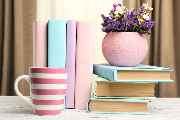 Books, cup and plant on wooden table, closeup - 写真・画像