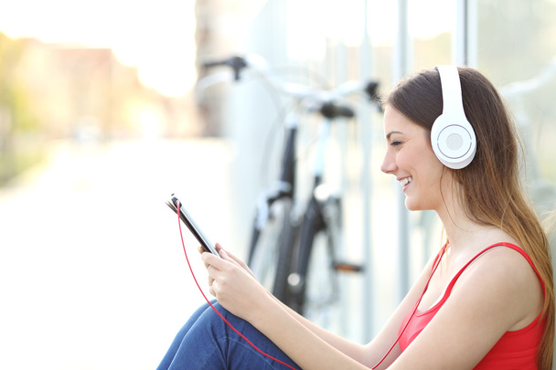 Woman listening to the music from a tablet in a park - Foto, Imagem