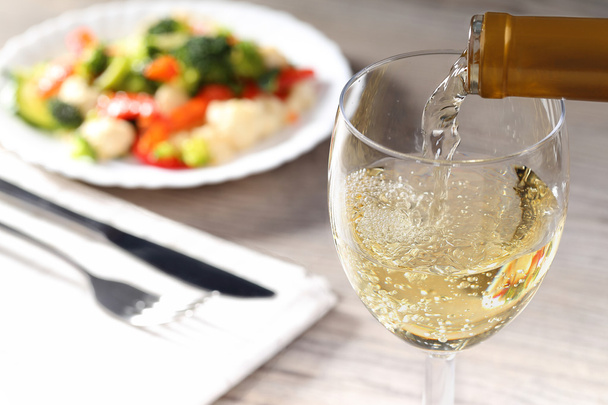 Verter vino blanco y ensalada
 - Foto, Imagen
