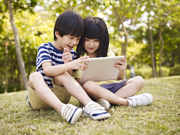 two asian children using tablet outdoors - Photo, Image
